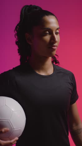 Vertical-Video-Studio-Portrait-Of-Woman-Wearing-Sports-Clothing-Holding-Ball-Against-Coloured-Background